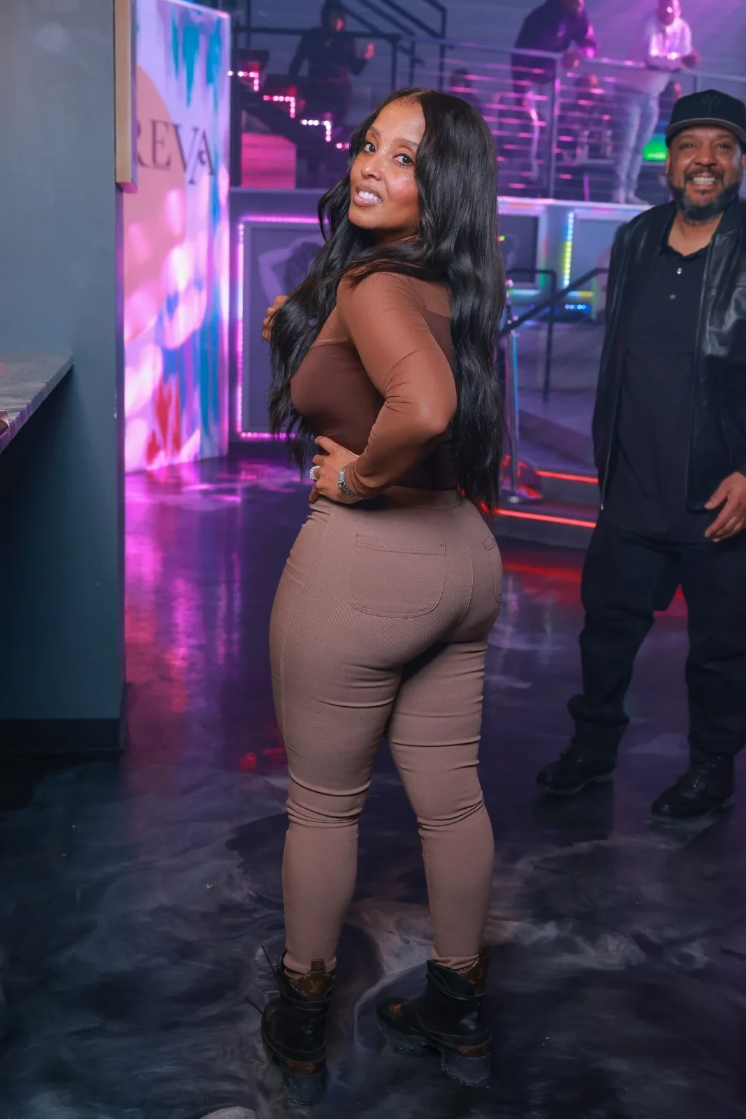 Preva 2-21-25 Friday A stylish woman posing at Preva nightclub in Detroit, with vibrant neon lights and an energetic crowd in the background.